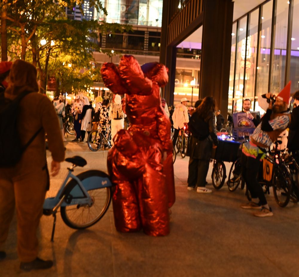A person in a large Jeff Koonz metal balloon dog sculpture