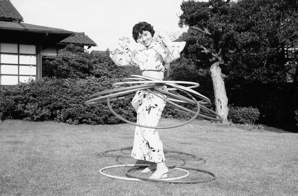 Photo of a Japanese (I think) woman using several hula hoops at the same time. 