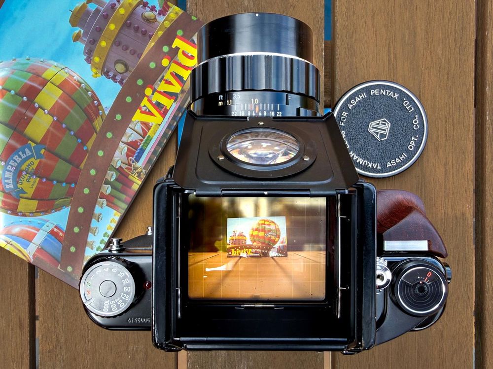 Photo of the Vivid Zine and the camera I used to make my contribution, the Pentax 6x7. The zine was themed around the title, “Vivid”, plus the film stock Kodak Gold 200 with each contributor making their own interpretations of the subject. This is the 4th Zine produced by the Photozine Collective in honour of the late John Whitmore, with proceeds going to charity. The zine can be bought here (https://ko-fi.com/s/2480367504). The Photozine Collective has an account on Bluesky @Photozinecoll.bsky.social. 