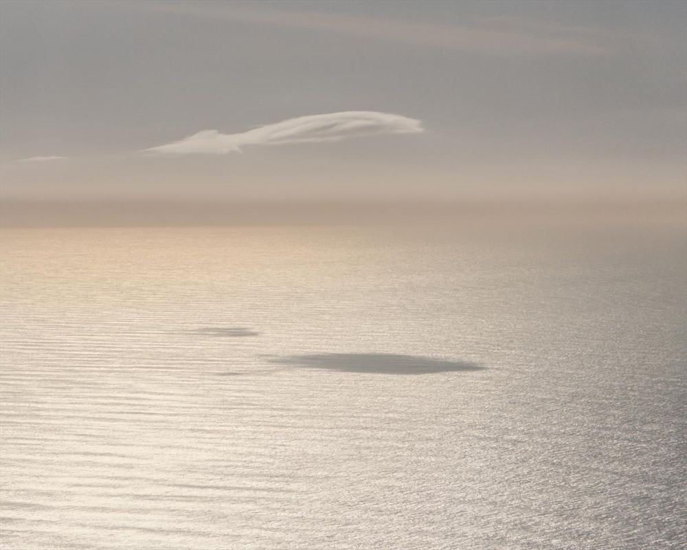 Photograph of a cloud and its shadow over the ocean. 