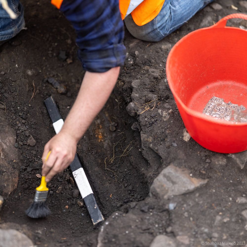 Person brushing something in a trench