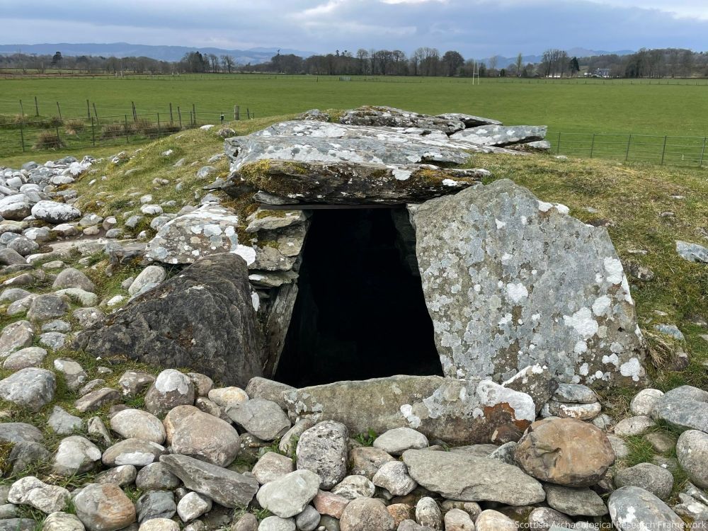 Stone and grass mound in a field with a large entrance