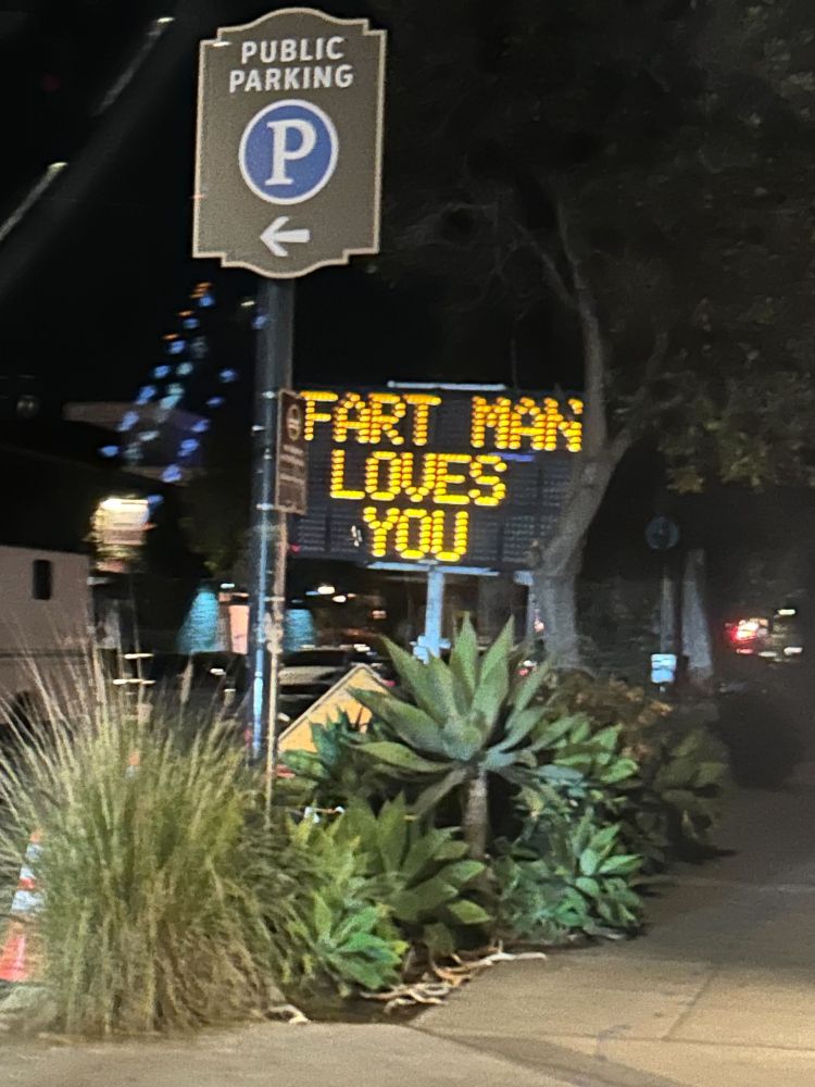 A weakly secured WANCO message sign reads "FART MAN LOVES YOU"