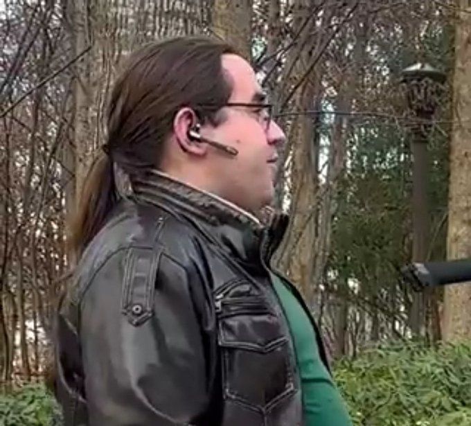 Image of a man in a green shirt and leather jacket. He has long brown hair tied in a ponytail. It is from a viral video in which the man rejects a false binary premise.