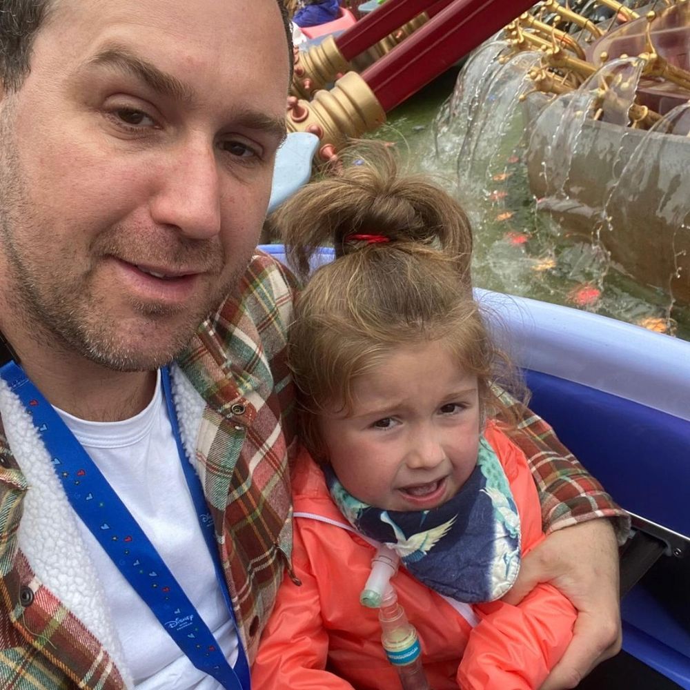 Selfie of dad and Daisy taken while riding Dumbo the Flying Elephant ride at Disneyland Paris. On the ride, Daisy and dad are flying over water and smiling for the camera.