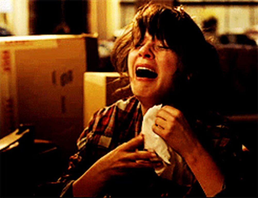 a woman is crying while holding a napkin in front of a box with the letter i on it