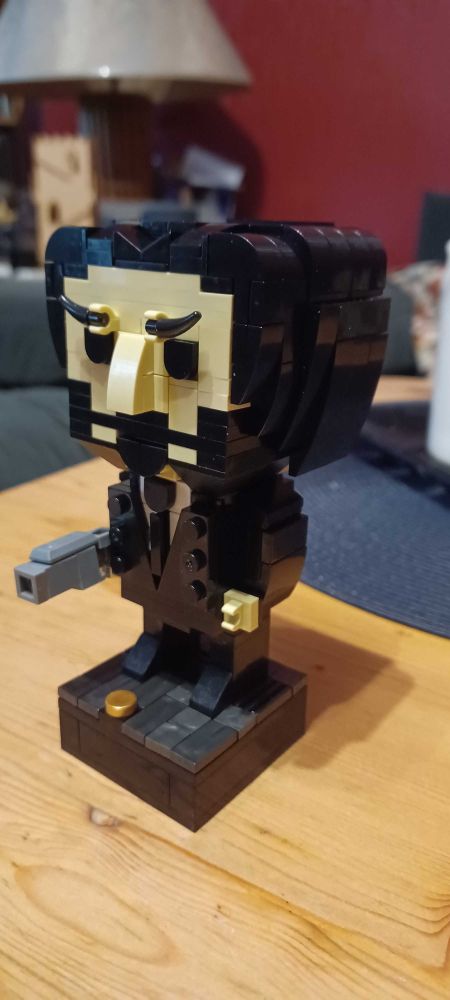 A figurine looking like the angry owner of a dog, who went on a killing spree after said dog was killed. Pretty known franchise with Keanu Reeves as the leading actor. the Fiigurine is built with Lego like building bricks, and kind of loooks like their Brickheads but was done by an alternative, german Brand called Bluebrixx.