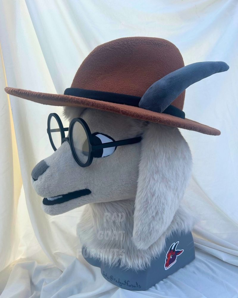 A different angle of the goat fursuit head. From this view you can see the hat has a black band around the base. 