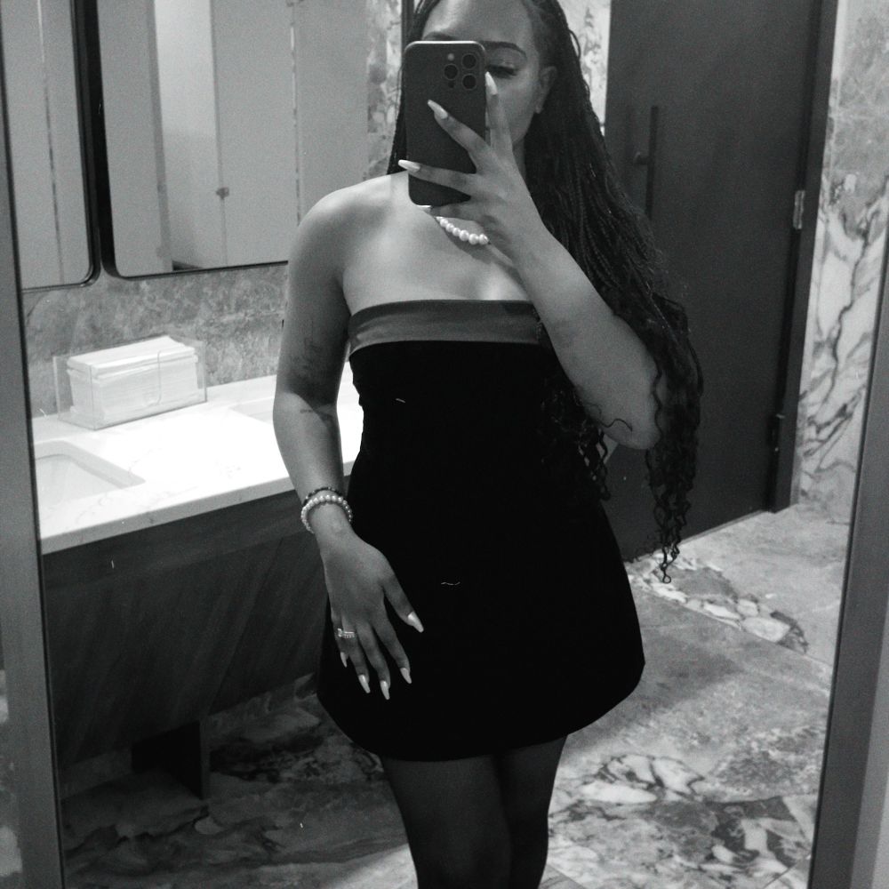 black and white filtered mirror photo of black woman posing with fitted dress on