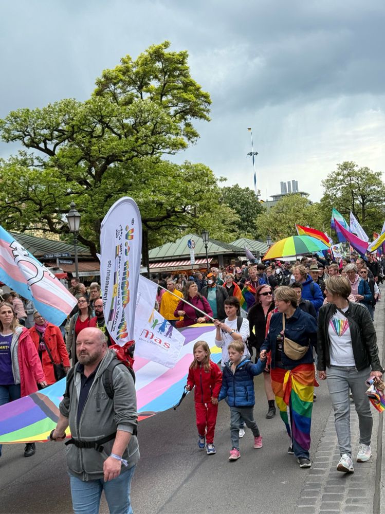 A pride parade through the streets of Munich with trans flags, people in colorful attire