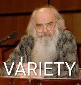 Stafford beer, old and grumpy, holding a glass of unknown contents, seated at a speakers podium. All is low res, including the very large single word caption: VARIETY