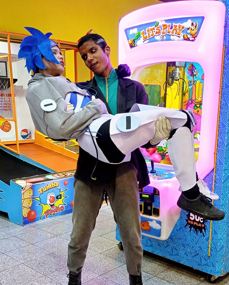people cosplaying Gwendroid and Andi at an arcade. Andi is carrying Gwen in his arms
