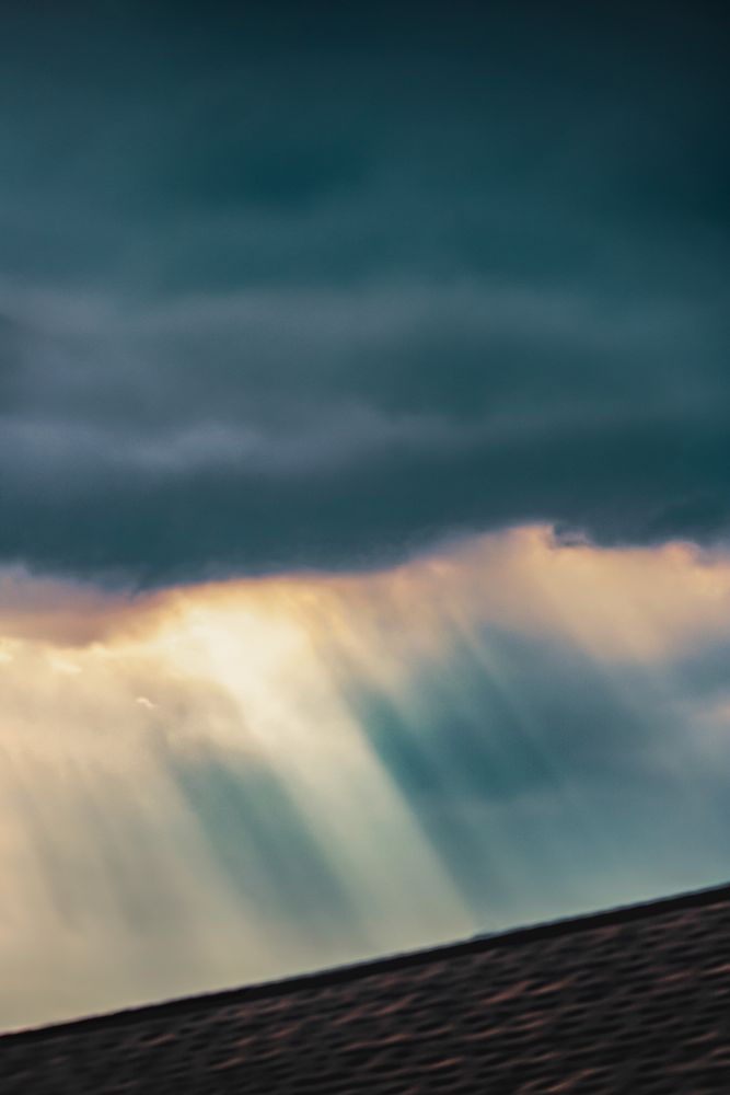 Color variation of a black and white I shared a week or so ago. Golden light rays of sunlight come down from a greyish-blue storm cloud 