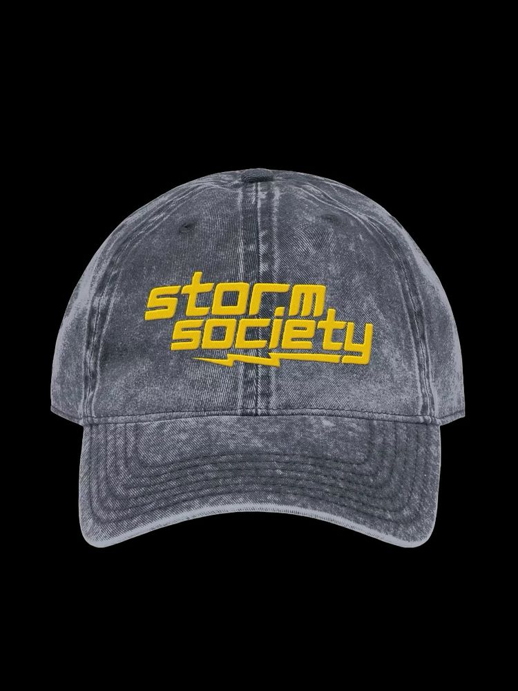 A distressed relaxed-fit hat in blue denim with a yellow storm society logo 