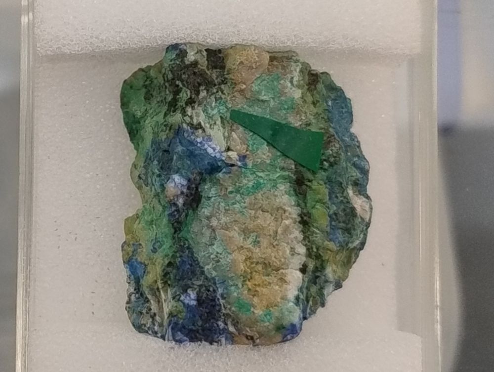 Tiny blue-green crystals (there's a green coloured arrow stuck on the specimen to point these out) with some leaf-green illite and blue azurite on a matrix. From Bambollita Mine, Moctezuma, Sonora, Mexico.

Specimen from the Natural History Museum, London's collections.