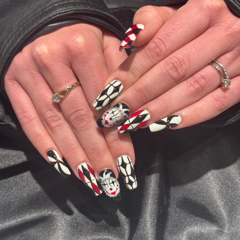 Black, white, and red manicure with triangles and swirls with a clown face on the third finger 