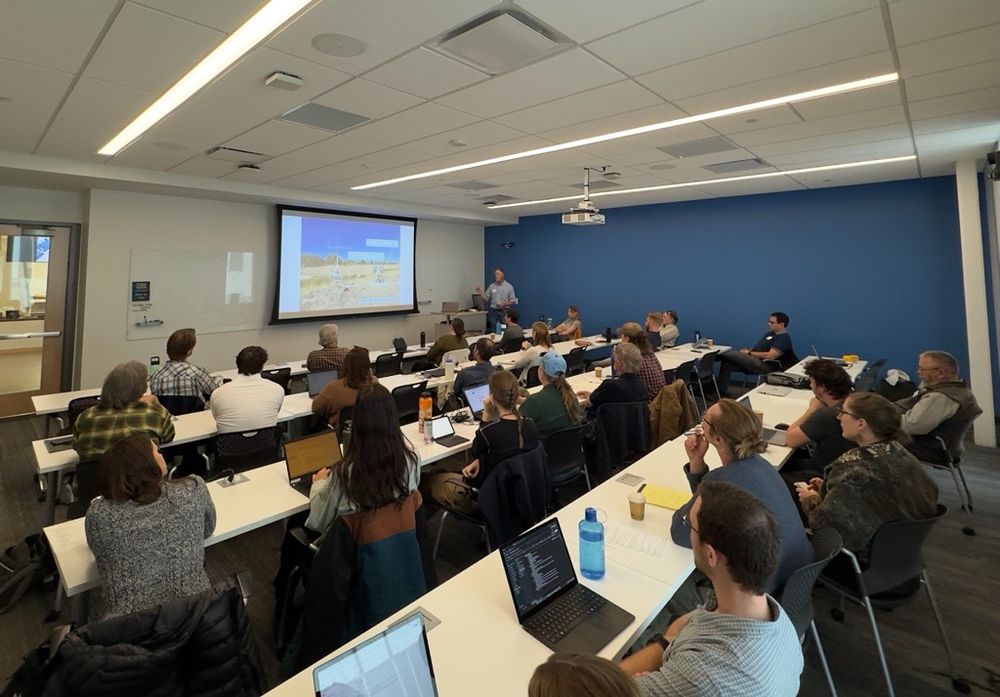 A classroom full of people watching a presenter, who is discussing a slide showing a CoAgMET weather station
