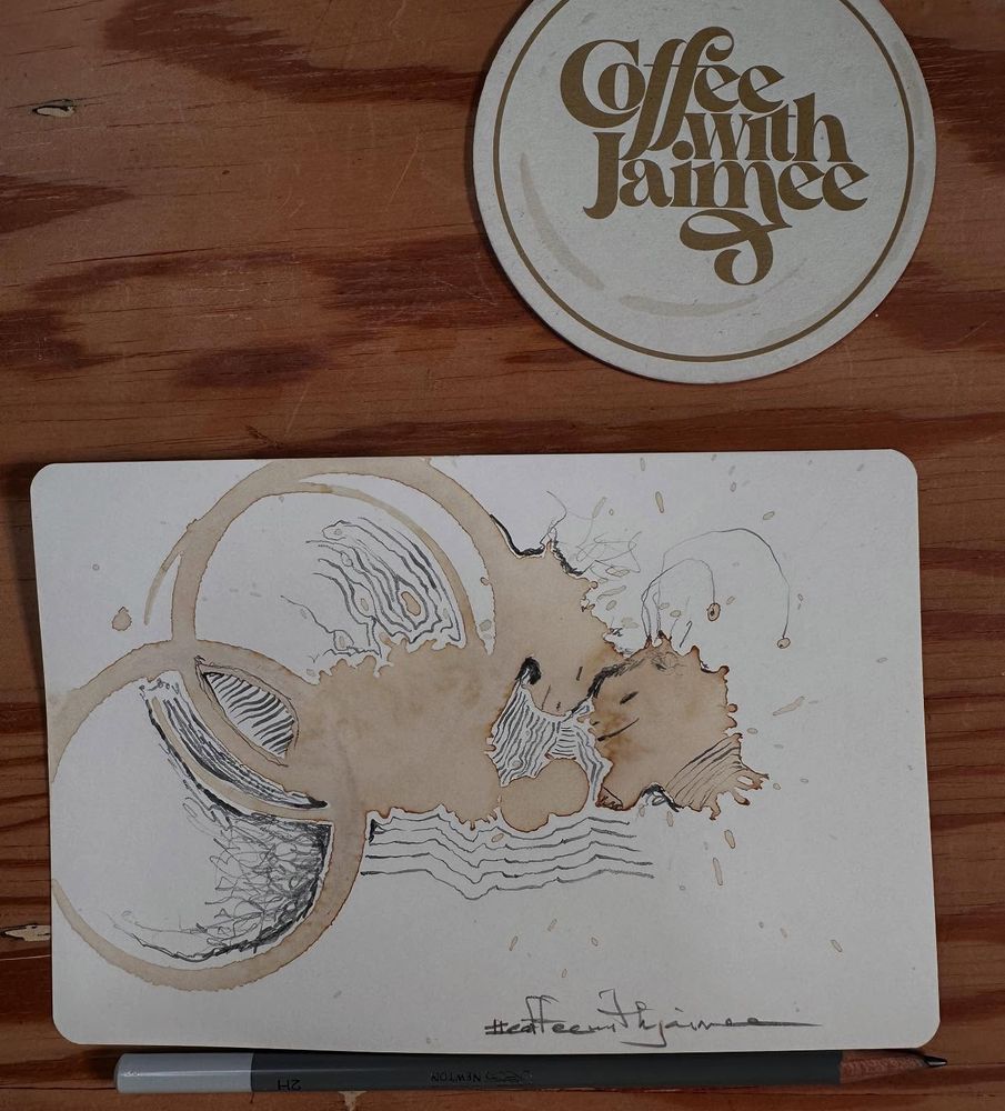 Doodles over dried coffee spills that look like two strange beings with foreheads touching and eyes closed.