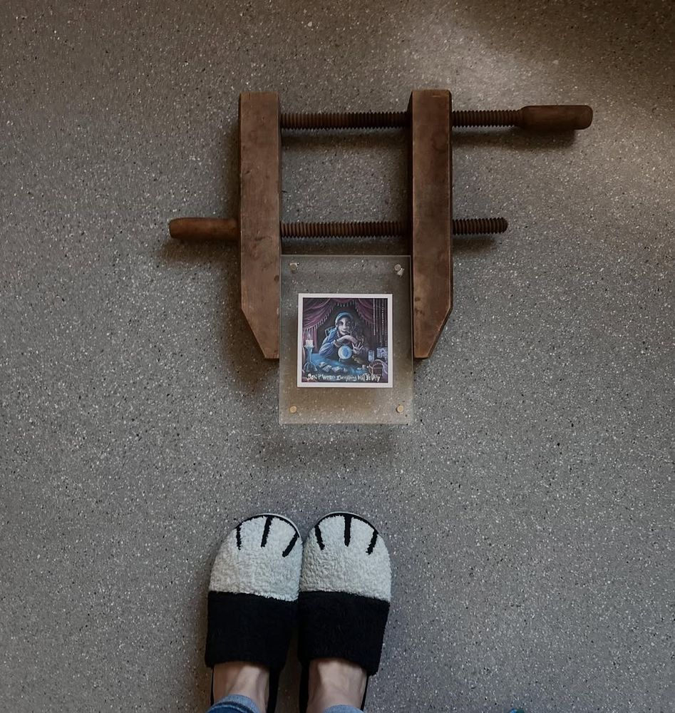 Antique woodworking clamp, clamping an acrylic frame featuring a copy of American Artist Jett Jackson's "Don’t Worry Everything Will Be Okay"(1958)