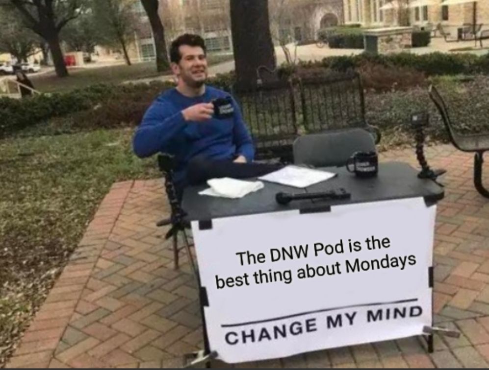 Stephen Crowder, a white man in a blue shirt holding a coffee cup while sitting behind a sign that says "The DNW Pod is the best thing about Mondays, change my mind". 
