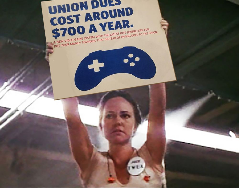 Norma Rae holds up a sign that says 