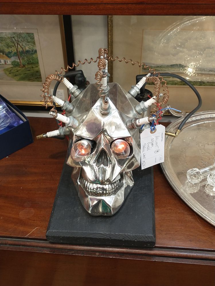 A silver skull with prominent electrodes and lightbulbs for eyes 