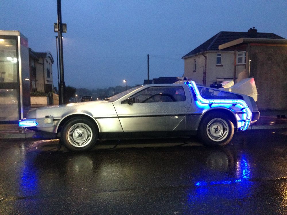 Delorean with Back to the Future modifications including neon lighting, on a rainy evening