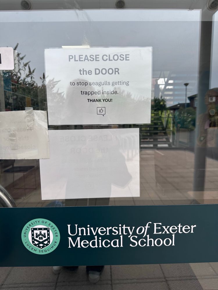 A sign on the door of the University of Exeter Medical school that says “Please close the door to stop the seagulls getting trapped inside.Thank you”