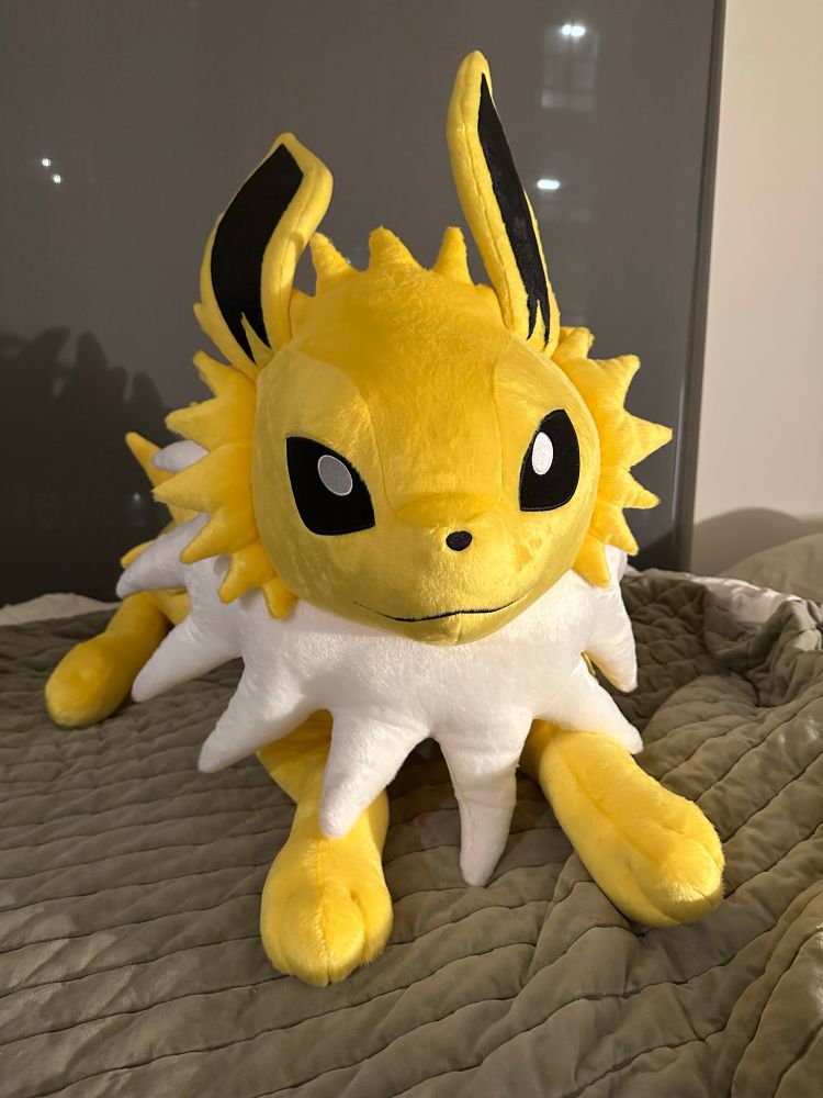a life size jolteon sitting on a green blanket