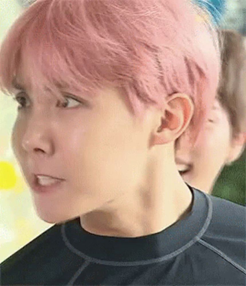 a close up of a person with pink hair and a black shirt .