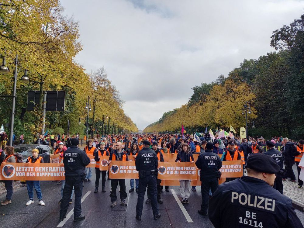 Viele Menschen, teilweise mit Fahnen und Bannern auf der Straße des 17. Juni in Berlin. Davor Polizei.