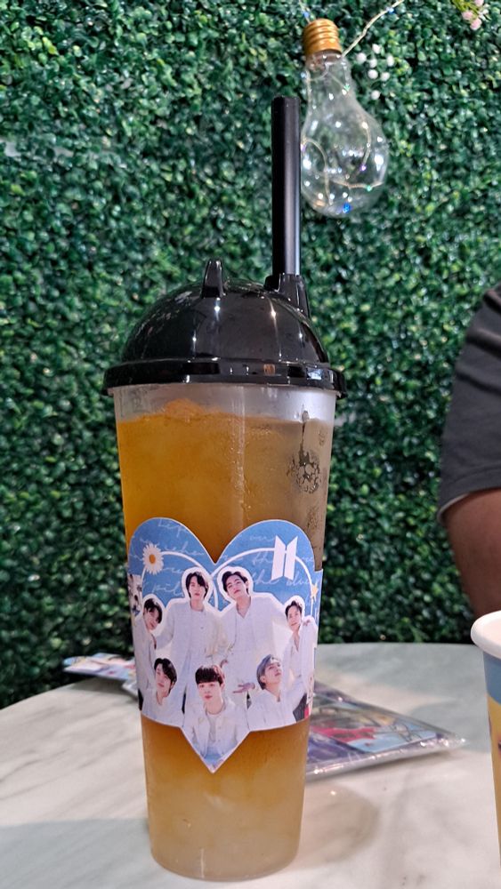 Photo of cafe table with an Iced tea and BTS paper sleeve