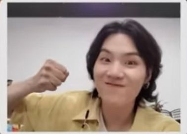 blurry close up of Yoongi in a yellow shirt with his fist up about to punch the screen
