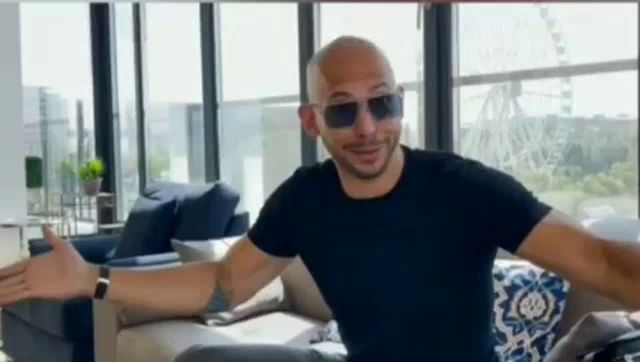 a bald man wearing sunglasses is sitting on a couch with his arms outstretched .