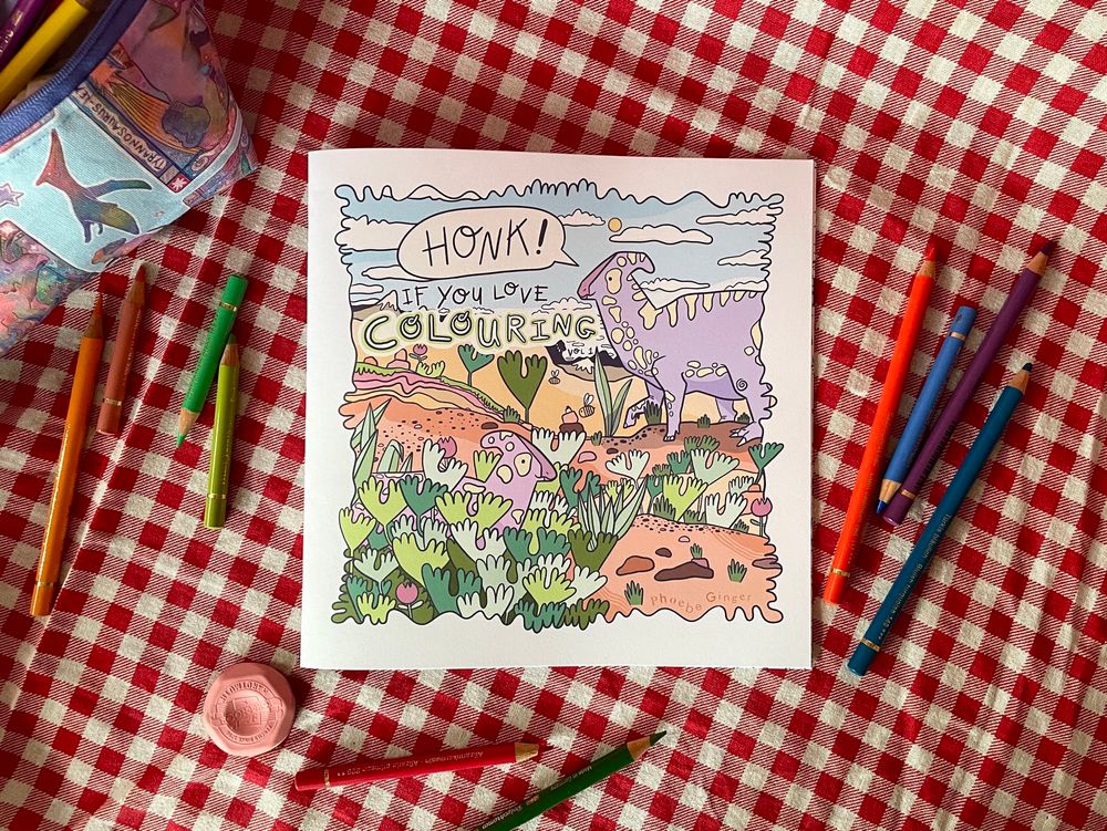 A flat-lay view of a dinosaur themed colouring book on a red gingham table cloth, surrounded by coloured pencils