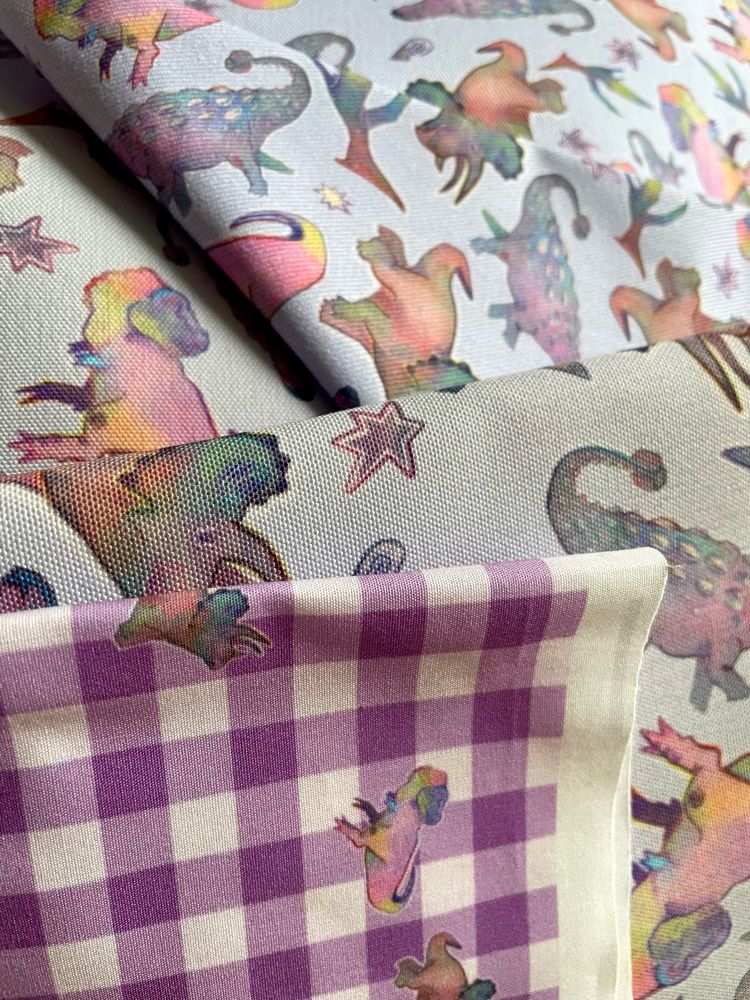 a selection of hand designed, custom printed dinosaur fabrics in purple gingham and Parma violet colours
