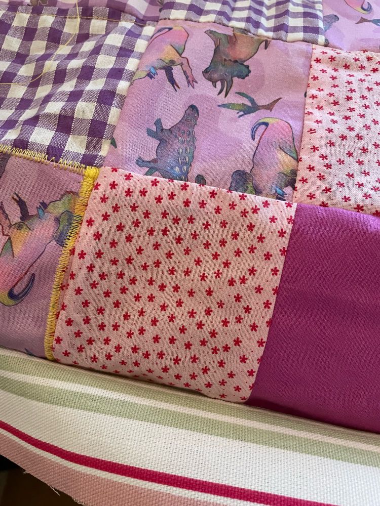 a close-up, progress photo of quilted pink and purple patterned fabrics