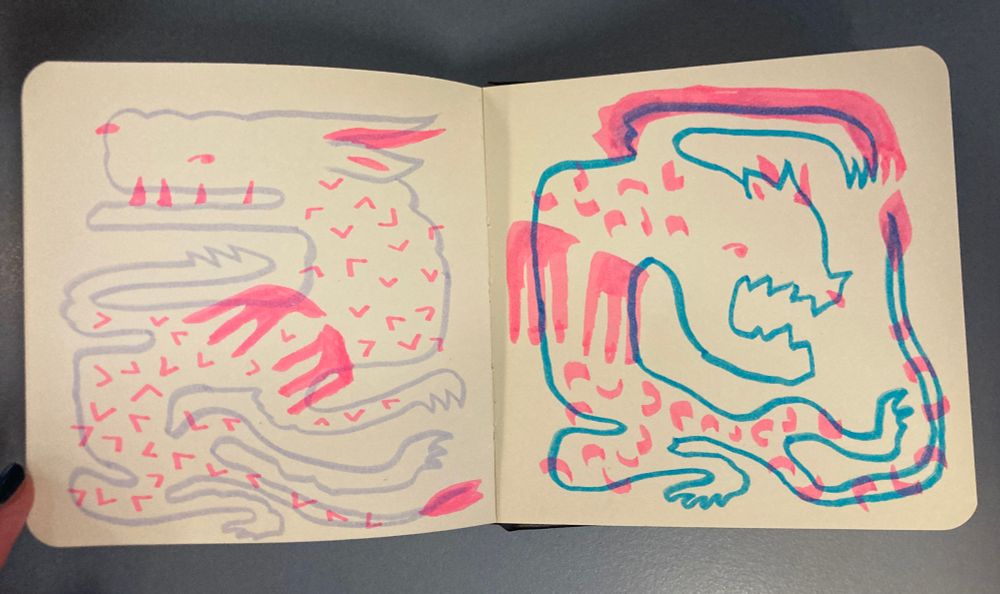 Photo d’un carnet ouvert sur une double page dessinée au feutre et surligneur fluo rose avec des dragons stylisés et rigolos