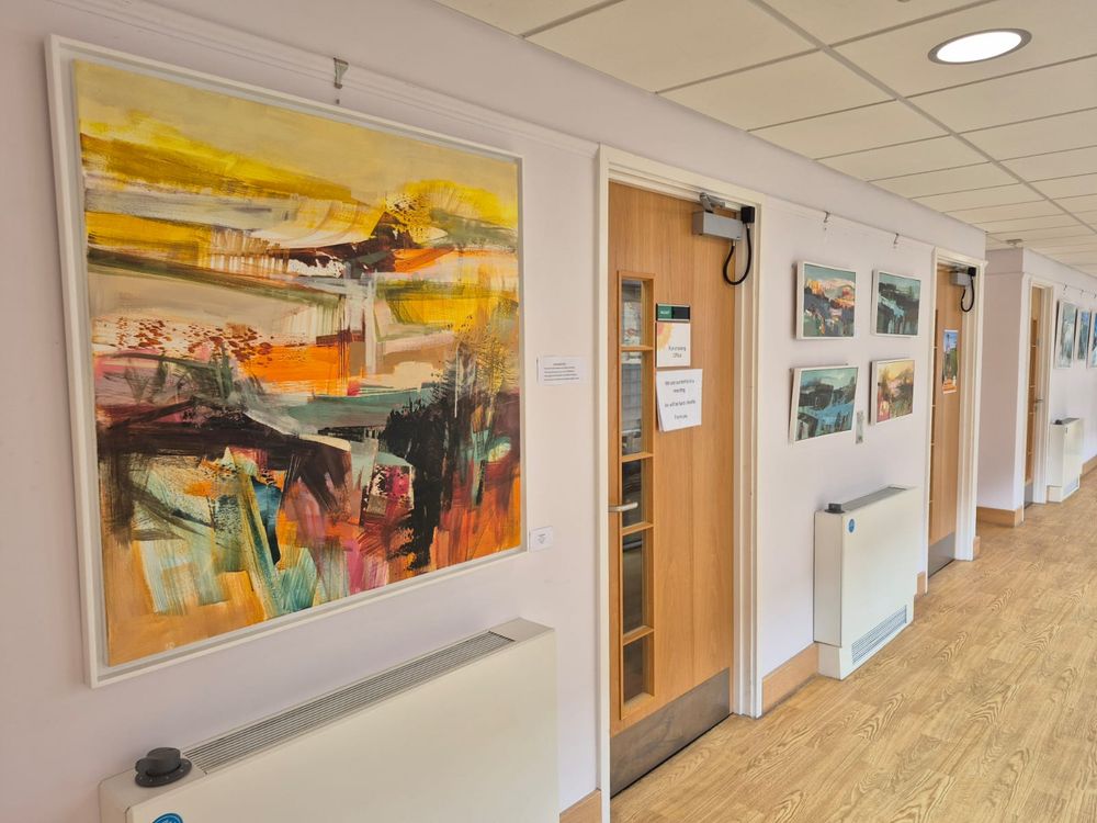 Paintings hanging on the wall of a long corridor as part of an art exhibition
