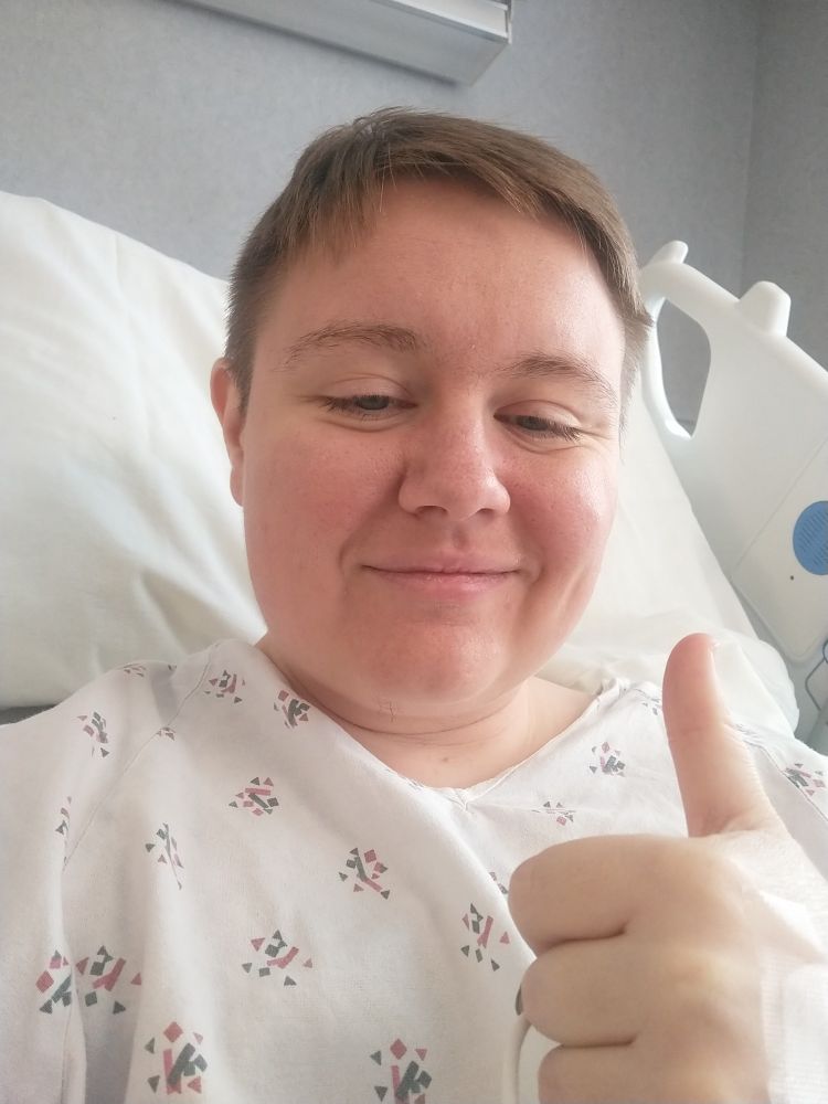 Man in hospital gown giving a thumbs up 