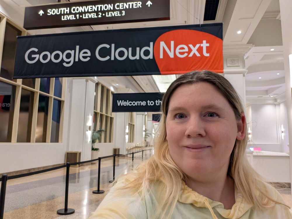 Girl standing in an open hallway with a sign above that says Google Cloud Next.