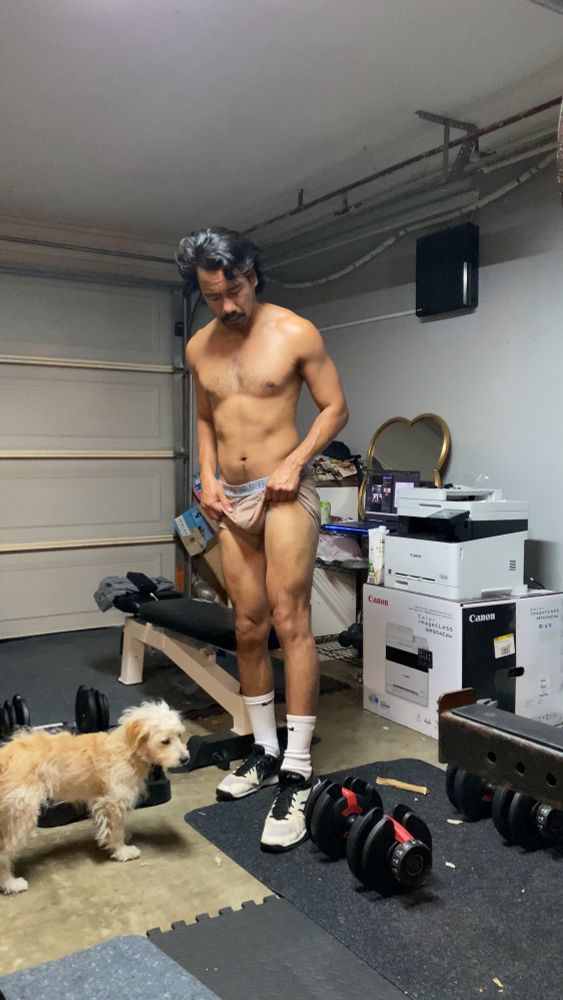 gay man flexing quads while his boxer briefs are pulled up. His dog is watching, worried for his mental health