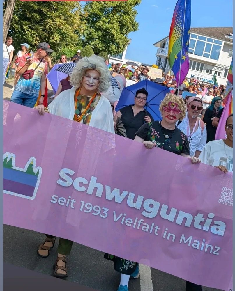 Die Drag Queen Igitte von Bingen mit einem Banner des Vereins Schwuguntia beim CSD Bingen.