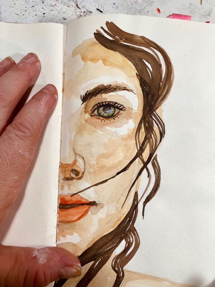 half portrait of a woman in a sketchbook, my left hand holding the pages.