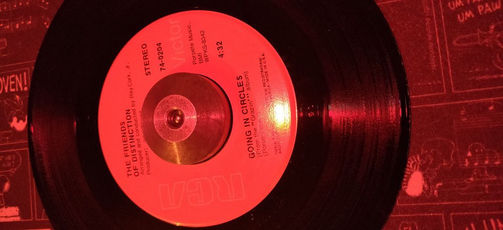 A 45 RPM record playing The Friends of Distinction's "Going in Circles".