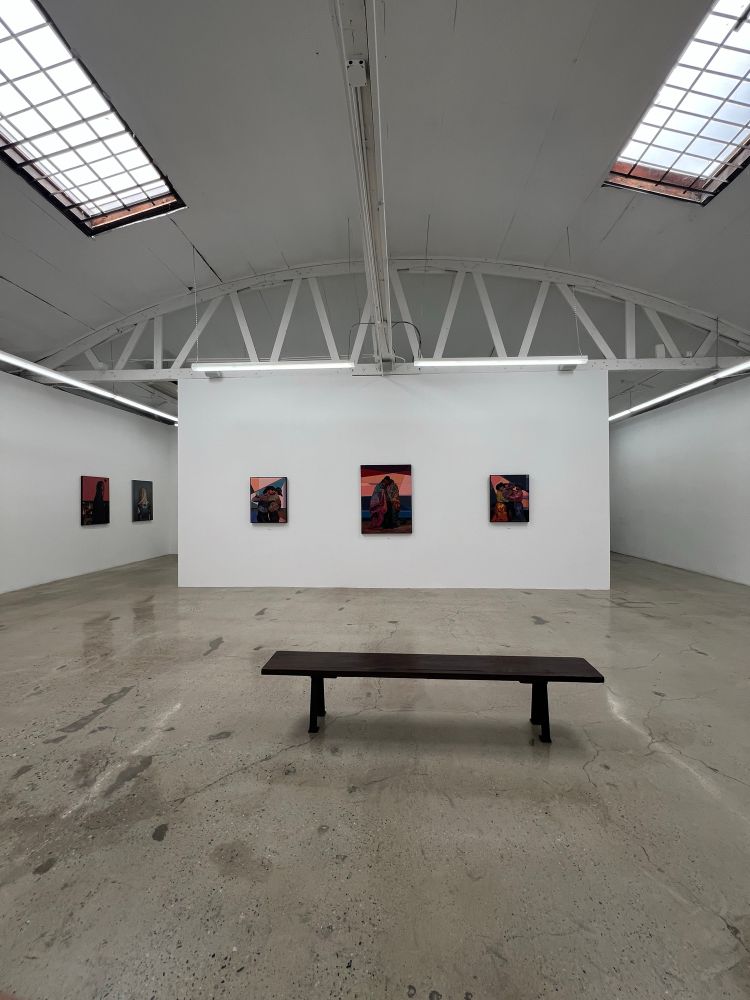 The installation feels intentional and reverent, with equal spacing and eye-level hanging.
	•	The central bench invites viewers into reflection and rest—positioned for meditative viewing.
	•	The lighting and white gallery walls highlight the saturated palette without distraction.
