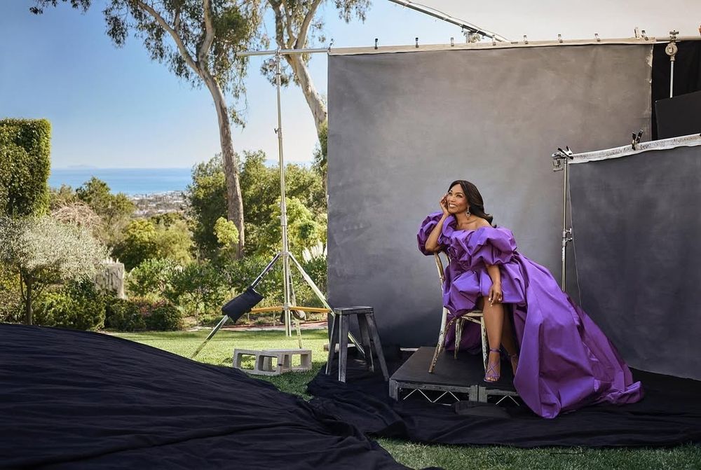 Angela wearing a purple dress in front of gray screens