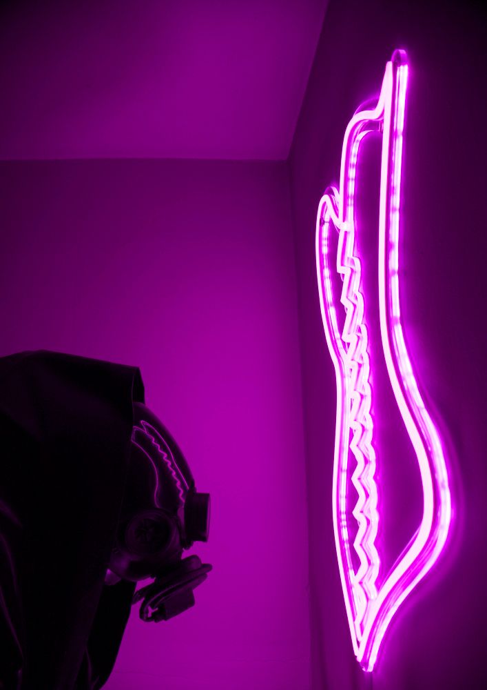 A person with a neon corset reflected in a gas mask visor.  