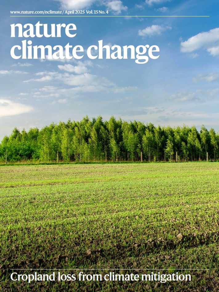 The image shows the April cover of journal, with the journal name over a photo of new shoots in a crop field, and a woodland in the distance. The line "Cropland loss from climate mitigation" describes the cover.