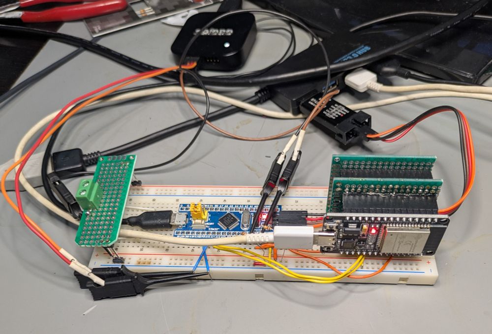 Breadboard with an STM32 blue pill, and an ESP32-Wroom de board.  There is a mess of wires, a logic analyzer, and other devices in frame.